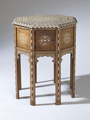 A photograph of a small, octagonal side table made from wood and inlaid with ivory and ebony in intricate geometric patterns.